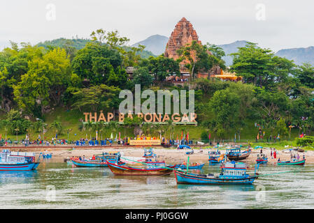 Nha Trang, Vietnam - Mai 5, 2018: Po Nagar Tempel zwischen Bäumen auf einem Hügel mit blauen Boote auf dem Cai Fluss unten & Menschen auf der ganzen Szene verteilt. Stockfoto