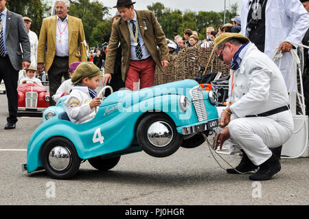 Kind settrington Cup Racing 'driver' in einem Austin J40 Pedal Car. Last minute Wartung Stockfoto