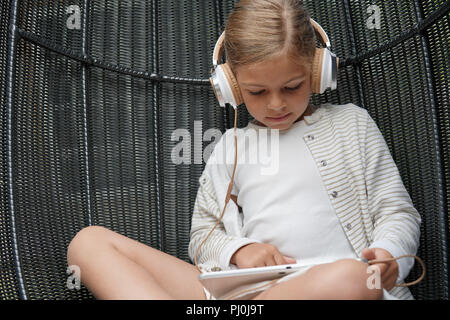 Kleines Mädchen mit Kopfhörer mit digitaler Tablet angeschlossen Stockfoto