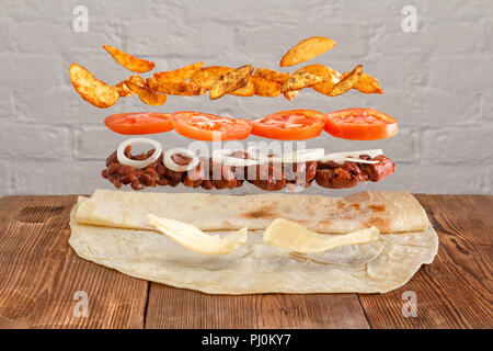 Shaurma. Ein traditionelles Gericht aus lavash Fleisch und Gemüse. Eine leavitating shawarma auf einer hölzernen Hintergrund. Stockfoto