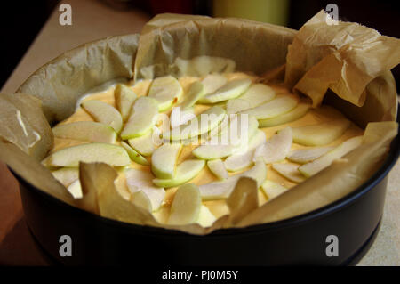 Rohe Kuchen mit Stücken von Apple in einer Form bereit zum Backen. Hefeteig für den Ofen zubereitet. Stockfoto