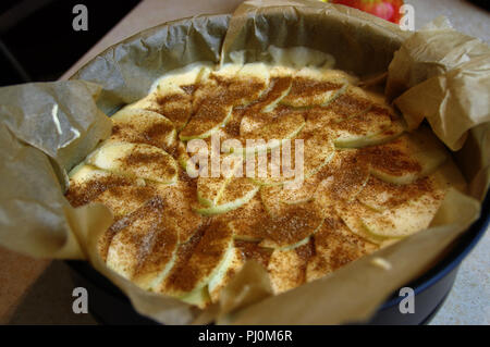 Rohe Kuchen mit Stücken von Apple in einer Form bereit zum Backen. Hefeteig mit Zimt für den Ofen zubereitet. Stockfoto