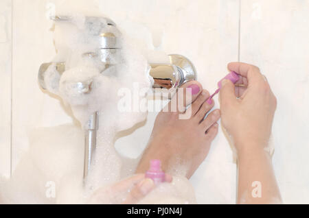 Die Frau in der Badewanne und Malen ihre Zehennägel in Rosa. Stockfoto