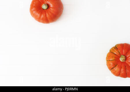 Herbst Rahmen aus orangefarbenen Hokkaido Kürbisse isoliert auf weißem Holztisch Hintergrund. Herbst, Halloween und Thanksgiving Konzept. Styled lieferbar flache Fotografie legen. Ansicht von oben. Der leere Raum für Text. Stockfoto