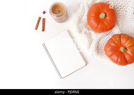 Herbst gemütliche Komposition. Mockup Szene mit leeren Notebook. Kürbisse, Kerze, Zimtstangen und Plaid auf weißem Hintergrund gestrickt. Erntedank, Herbst, halloween Konzept. Flach, Ansicht von oben. Stockfoto