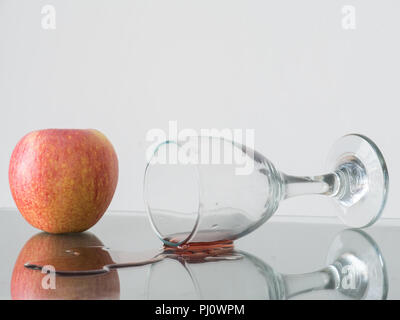 Wein Glas fallen mit Apple hinter auf weißem Hintergrund, Stockfoto