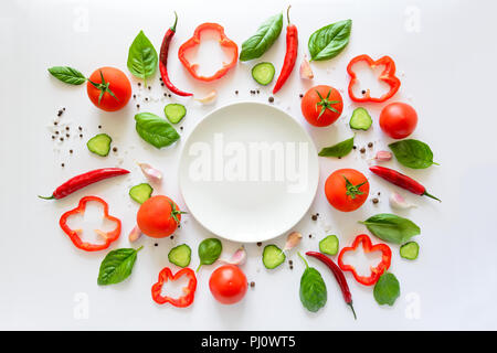 Bunter Salat Zutaten Muster aus Tomaten, Pfeffer, Chili, Knoblauch, Gurkenscheiben, Basilikum und leeren Teller auf weißem Hintergrund. Kochen conce Stockfoto
