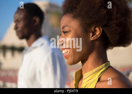 Closeup Portrait von zwei jungen schwarzen Rasse afrikanischer Mann und Frau lächelnd an die Sonne in Freiheit Outdoor Freizeitaktivitäten Aktivität zusammen. Schöne afro Paar Stockfoto