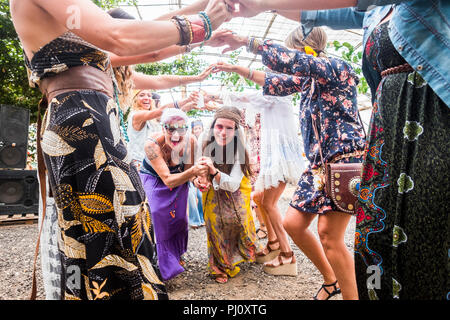 Gruppe von Frauen Menschen genießen die party Festival mit Tanz und Freude und spielerische Tätigkeit zusammen feiern. Buntes Kleid wie Hippie style und a Stockfoto