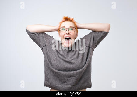 Portrait von stilvollen, gealtert, charmant, überrascht, schockiert Frau mit roten Frisur, Hände auf den Kopf Stockfoto