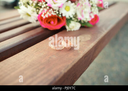 Gold Trauringe auf einen Strauß Rosen Stockfoto