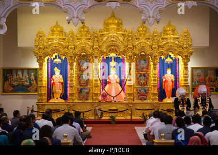 Anbeter vor Gottheiten am Kingsbury Hindu Tempel: MANINAGAR SHREE SWAMINARAYAN GADI SANSTHAN Stockfoto