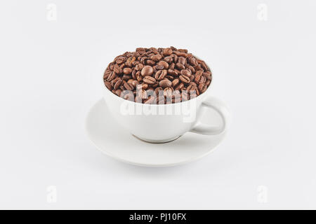 Weiß Kaffeetasse mit Kaffeebohnen auf einer Untertasse gefüllt, auf weißem Hintergrund. Ansicht leicht von oben. Stockfoto