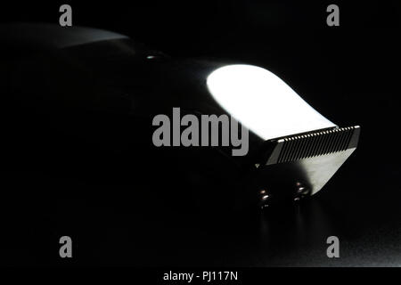 Friseur- Tools. Grooming Trimmer für Haare schneiden oder Bärte. Reflektierende Chrom auf schwarzem Hintergrund. Salon Ausrüstung. Stockfoto