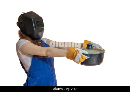 Das Mädchen in der Arbeitskleidung und Schweiß-Maske hält eine Pfanne in der Hand nach vorne verlängert. Stockfoto