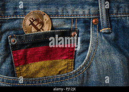 Golden BITCOIN (BTC) cryptocurrency in der Tasche der Jeans mit der Flagge von Deutschland auf Jeans Denim Textur. Stockfoto