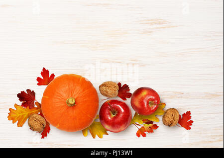 Runde Kürbis, Apfel und Walnüsse mit Herbstlaub auf weißem Holz- Hintergrund. Ansicht von oben. Flach. Stockfoto