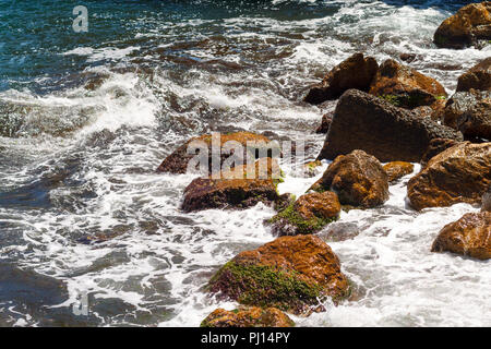 Steine am Strand, über die die Wellen schlagen werden Stockfoto