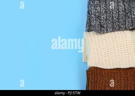 Warme gestrickte Pullover. Stapel aus Gewirken Kleider auf blauem Hintergrund, Pullover, Strickwaren, Platz für Text, Herbst Winter Konzept. Ansicht von oben Stockfoto