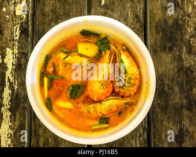 Thai Tom Yum Garnelen Suppe, würzig mit Kokosmilch in eine Schüssel sitzen auf einem alten Holztisch. Stockfoto