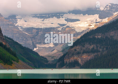 Menschen in Kajaks und Kanus navigieren Lake Louise mit Mt Victoria und Victoria Glacier droht in der Zukunft. Stockfoto