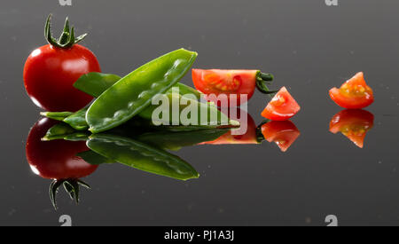 Satz von grünen Bohnen und Tomaten auf Acrylglas. Stockfoto