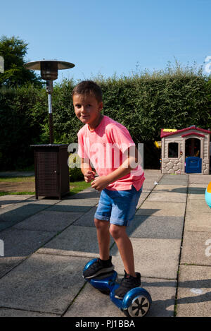 Junge 7 Jahre alter Junge Reiter eine Hover Board in seinem Garten, England, UK. Stockfoto