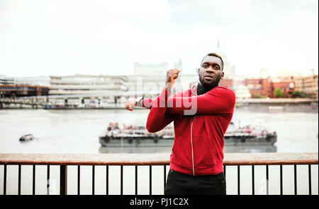 Junge sportliche schwarze Mann Runner zu tun Stretching auf der Brücke außerhalb in einer Stadt. Stockfoto