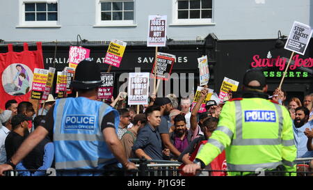 Eine Gruppe von Menschen, die Slogans bei einem EDL-Protest hielten, mit zwei Polizisten, die von hinten gesehen wurden, Worcester, Großbritannien. Stockfoto