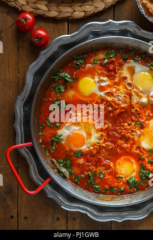 Würzige Shakshuka in einer Pfanne mit parskey, Brot und Hummus, Ansicht schließen Stockfoto