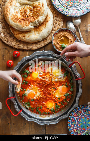 Leckeres Frühstück mit Familie shakshuka, Brot und Hummus. Im rustikalen Stil Stockfoto