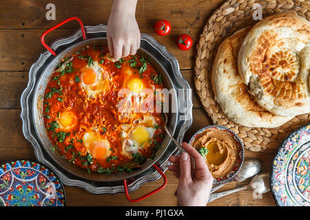 Leckeres Frühstück mit Familie shakshuka, Brot und Hummus. Im rustikalen Stil Stockfoto