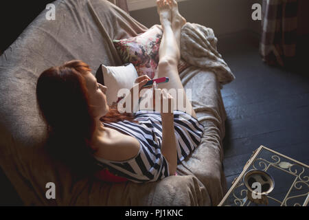 Frau mit Nagelfeile auf dem Sofa Stockfoto