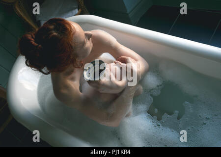 Frau mit Kaffee in der Badewanne im Badezimmer Stockfoto