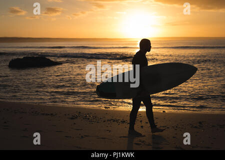 Surfer mit Surfbrett zu Fuß am Strand Stockfoto