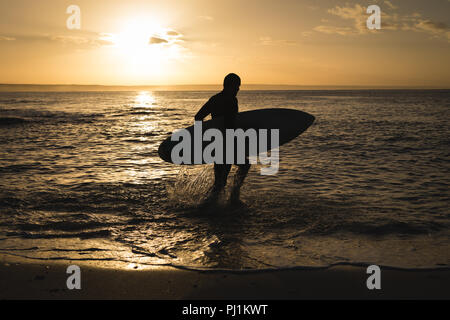 Surfer mit Surfbrett zu Fuß am Strand. Stockfoto