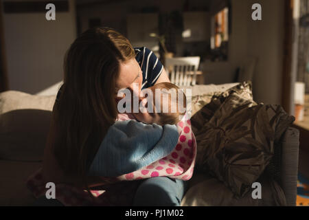 Mutter küssen, ihr Baby auf dem Sofa Stockfoto