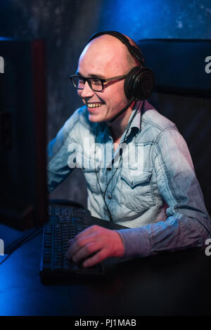 Hübscher Junge Spieler in Brille und Kopfhörer Computerspiel und schreien zu Hause begeistert Stockfoto