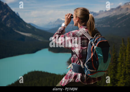 Weibliche Wanderer durch ein Fernglas in der Landschaft suchen Stockfoto