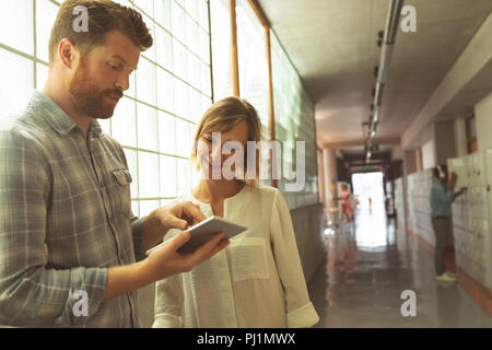 Führungskräfte sprechen über digitale Tablette im Korridor Stockfoto