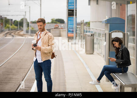 Pendler mit Handy in der Plattform Stockfoto