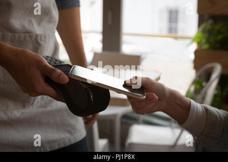 Frau Zahlung mit der NFC-Technologie auf Handy im Cafe Stockfoto