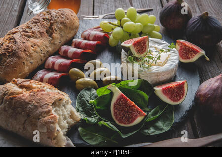 Camembert, Feigen, jamon, Honig und hausgemachtem Brot, auf dunklen, das Brett über rustikal Hintergrund Stockfoto