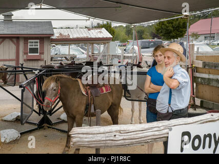 Alte mennonitischen Kollegen hat ein Pony reiten Business bei St, Jakob, Markt. Eine junge Frau, die ihm hilft. Stockfoto