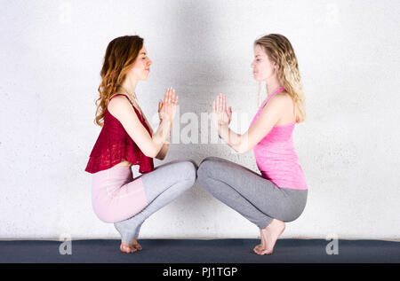 Zwei attraktive Sport Mädchen Yoga in einer Klasse. Gruppe von jungen Frauen, die sich in der Turnhalle Stockfoto