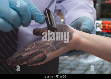 Der Polizist nimmt Fingerabdrücke von den Verdächtigen. Untersuchung der Kriminalität. Stockfoto