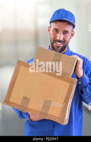 Lieferung Kerl halten großes Paket und lächelnd, isoliert auf weiss Stockfoto