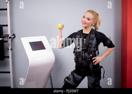 Fröhliche Blondine in EMS Anzug posiert für die Kamera Stockfoto