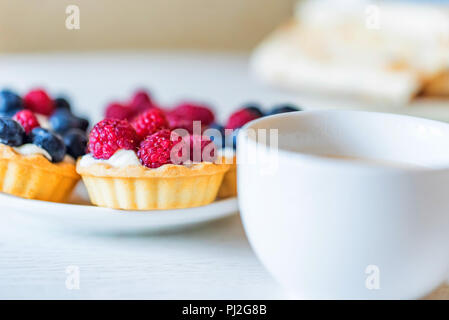 Süße Torten mit gemischten Beeren auf einer Platte Stockfoto