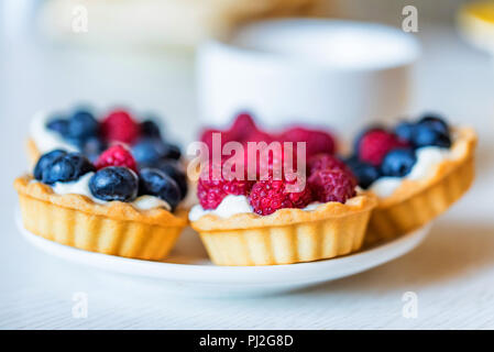 Süße Torten mit gemischten Beeren auf einer Platte Stockfoto